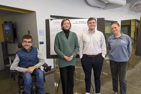 Three students with their instructor in front of their research posters