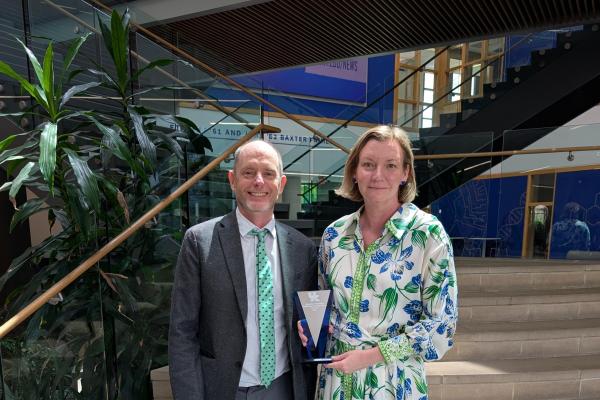 Dean and Dr. Curl standing in front of staircase holding award.