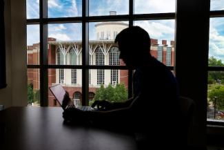 Outline of student studying with Willy T in the background through a window