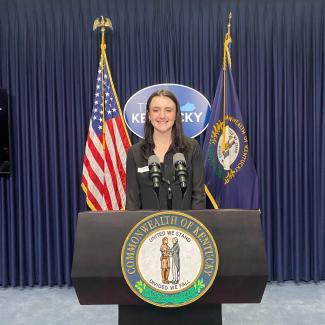 Public policy student, Olivia, posing behind governor's pressroom podium