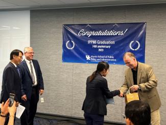 Student receiving graduation certificate at IPPM graduation