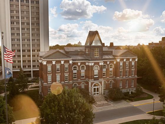 A picture of Patterson Office Tower and the Main Building with the sun in the background