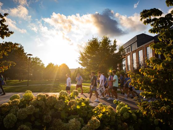 Students walking on campus with sun in background